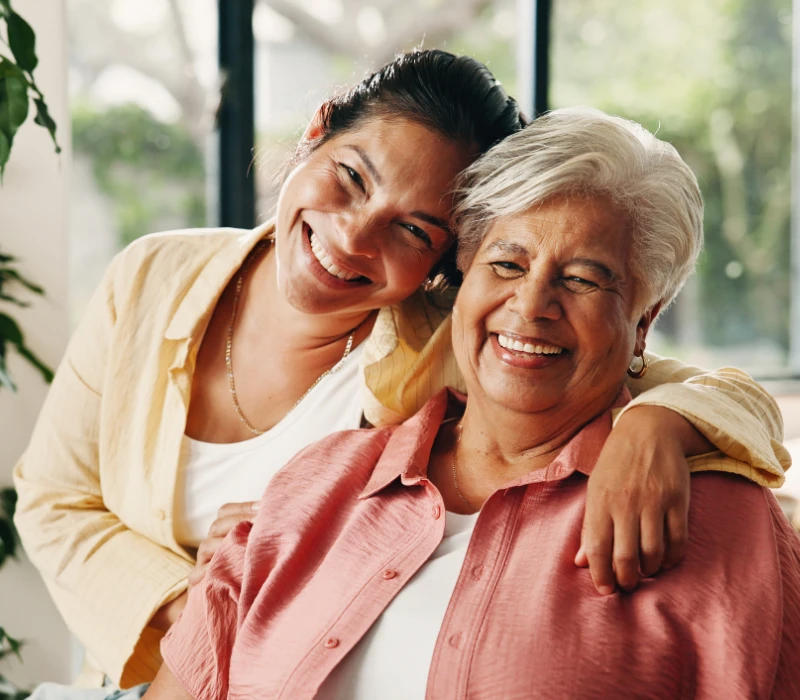 Mother and daughter hugging and smiling at camera