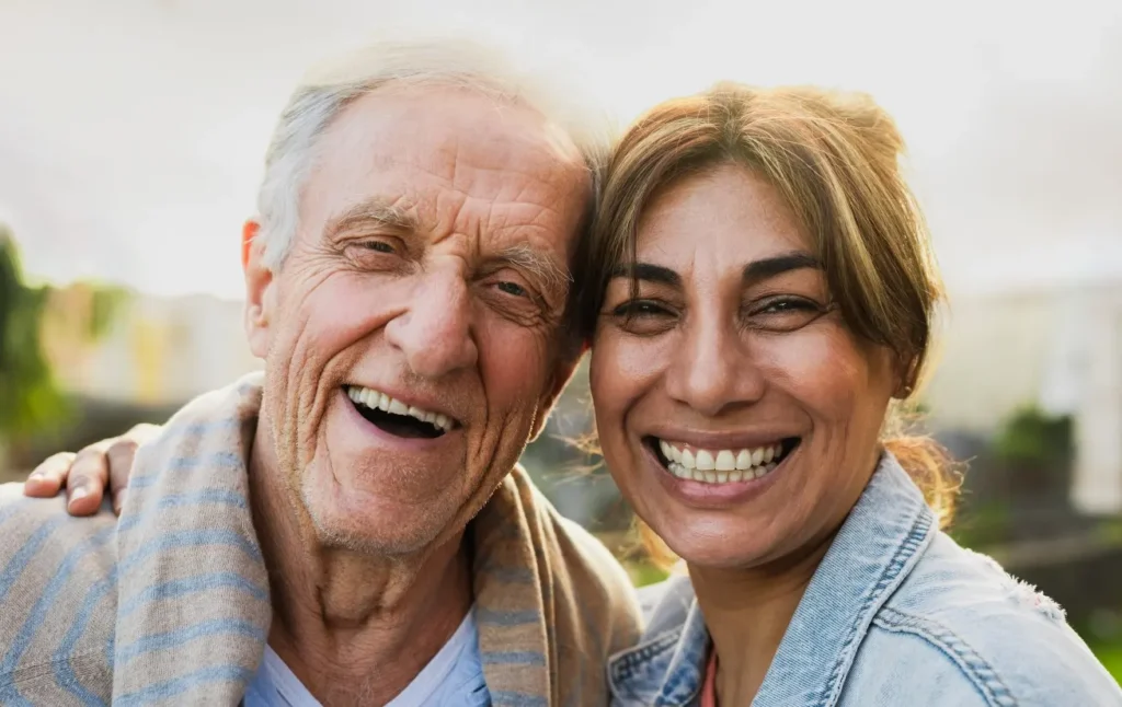Elderly man and support worker smiling at camera