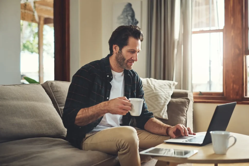 Man sitting on couch using laptop